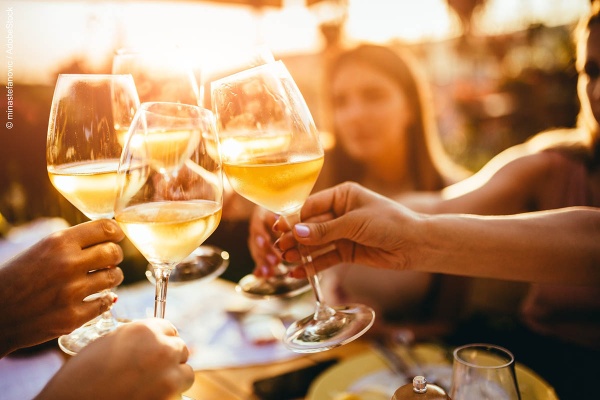 People clinking glasses with wine on the summer terrace of cafe or restaurant